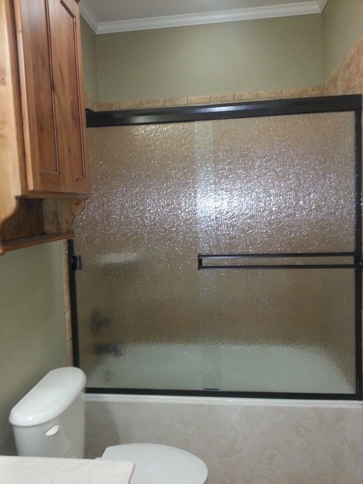 A bathroom with a bathtub , toilet , and sliding glass shower door.