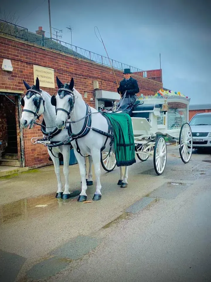 A horse drawn carriage is parked in front of a brick building.