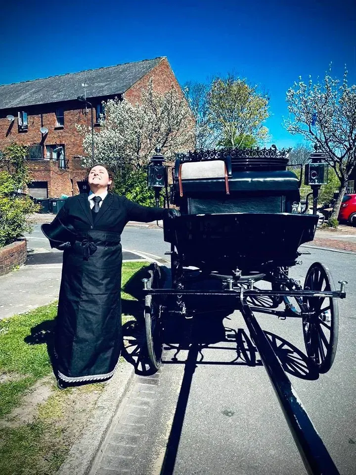 A man standing in front of a horse drawn carriage