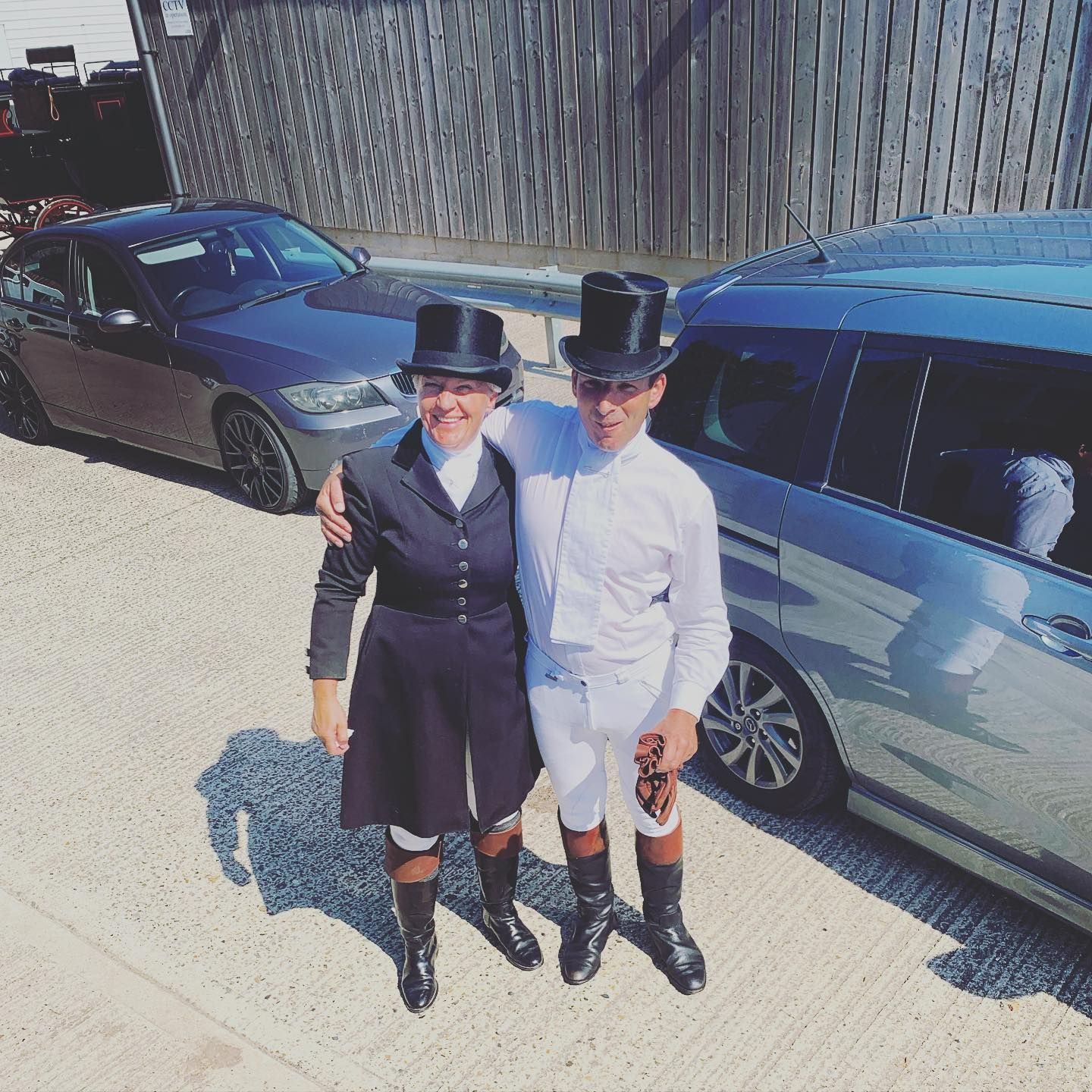 A man and a woman are posing for a picture in front of a car