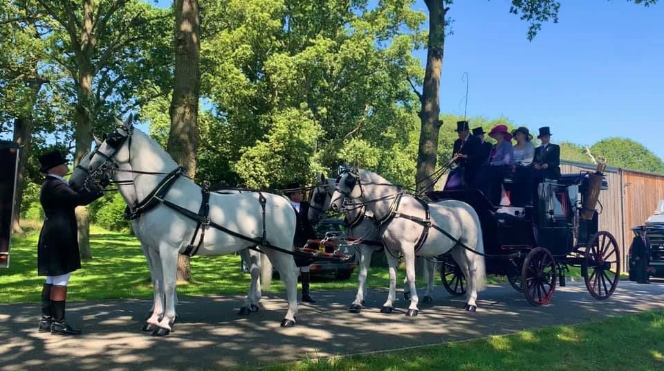 A group of horses pulling a carriage with people in it.