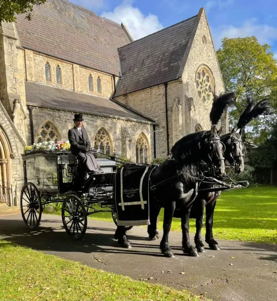 A horse drawn carriage is parked in front of a church.