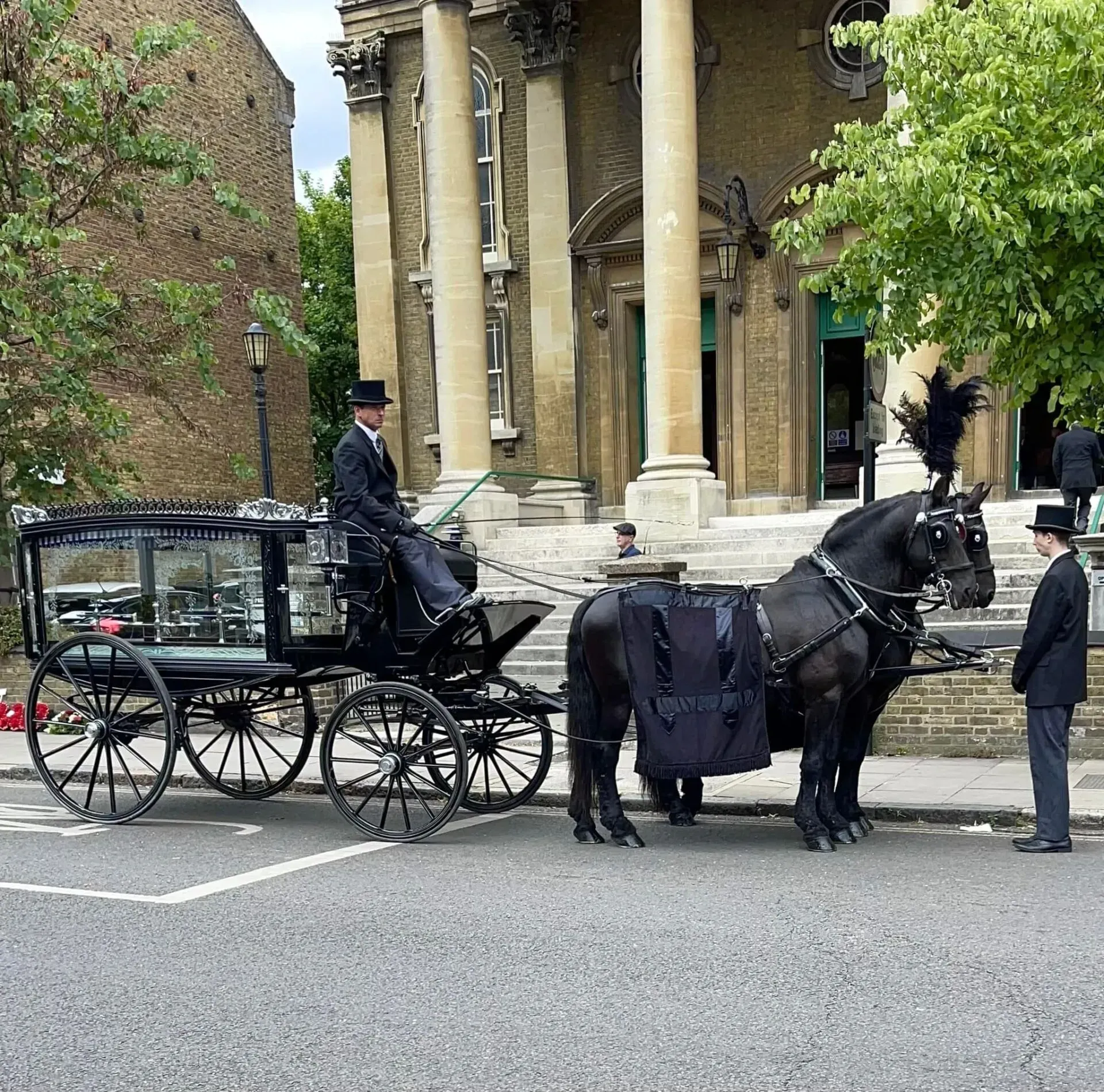 A horse drawn carriage is parked in front of a building