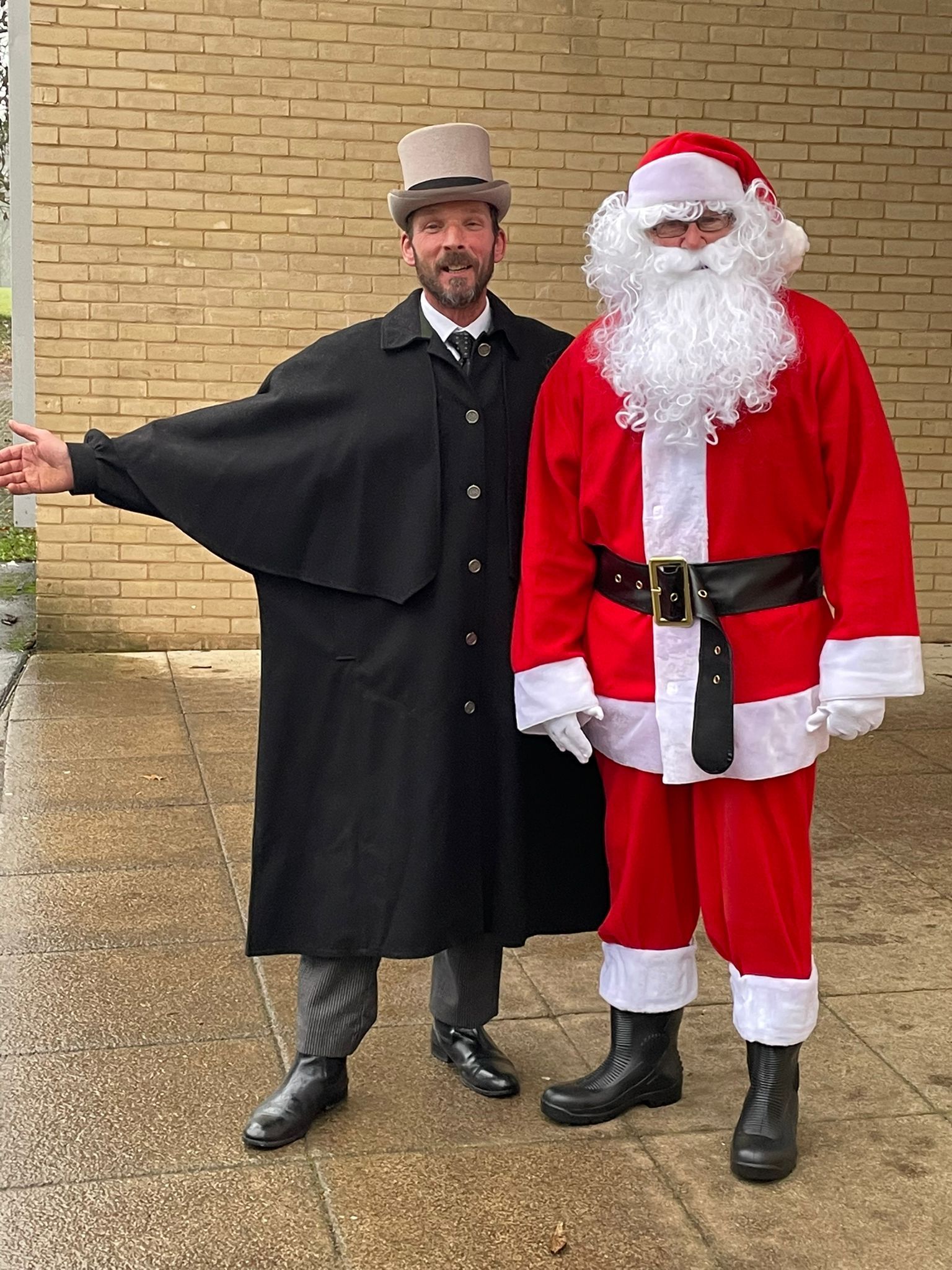 A man in a top hat is standing next to a man in a santa suit