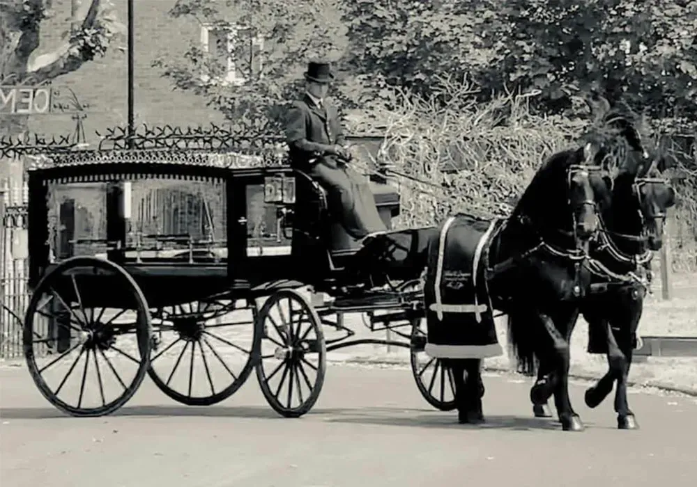 A black and white photo of a horse drawn carriage.