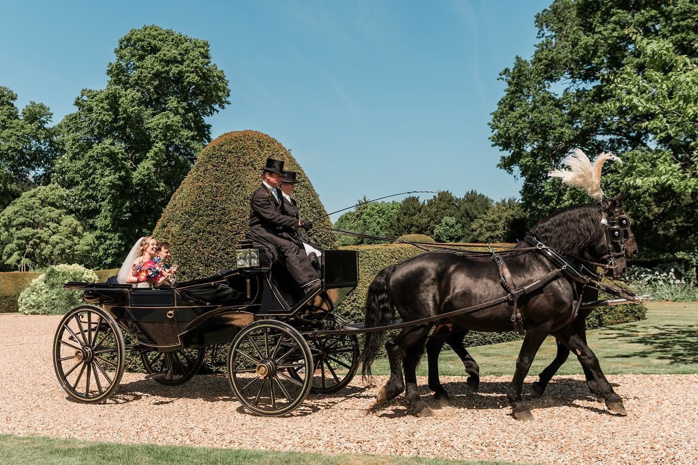 A man in a top hat is driving a horse drawn carriage
