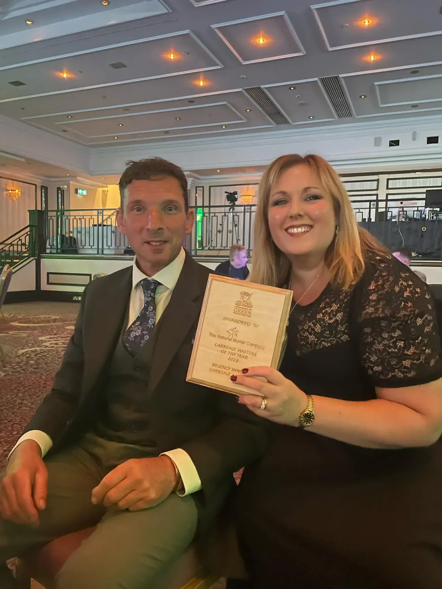 A man and a woman sitting next to each other holding a certificate