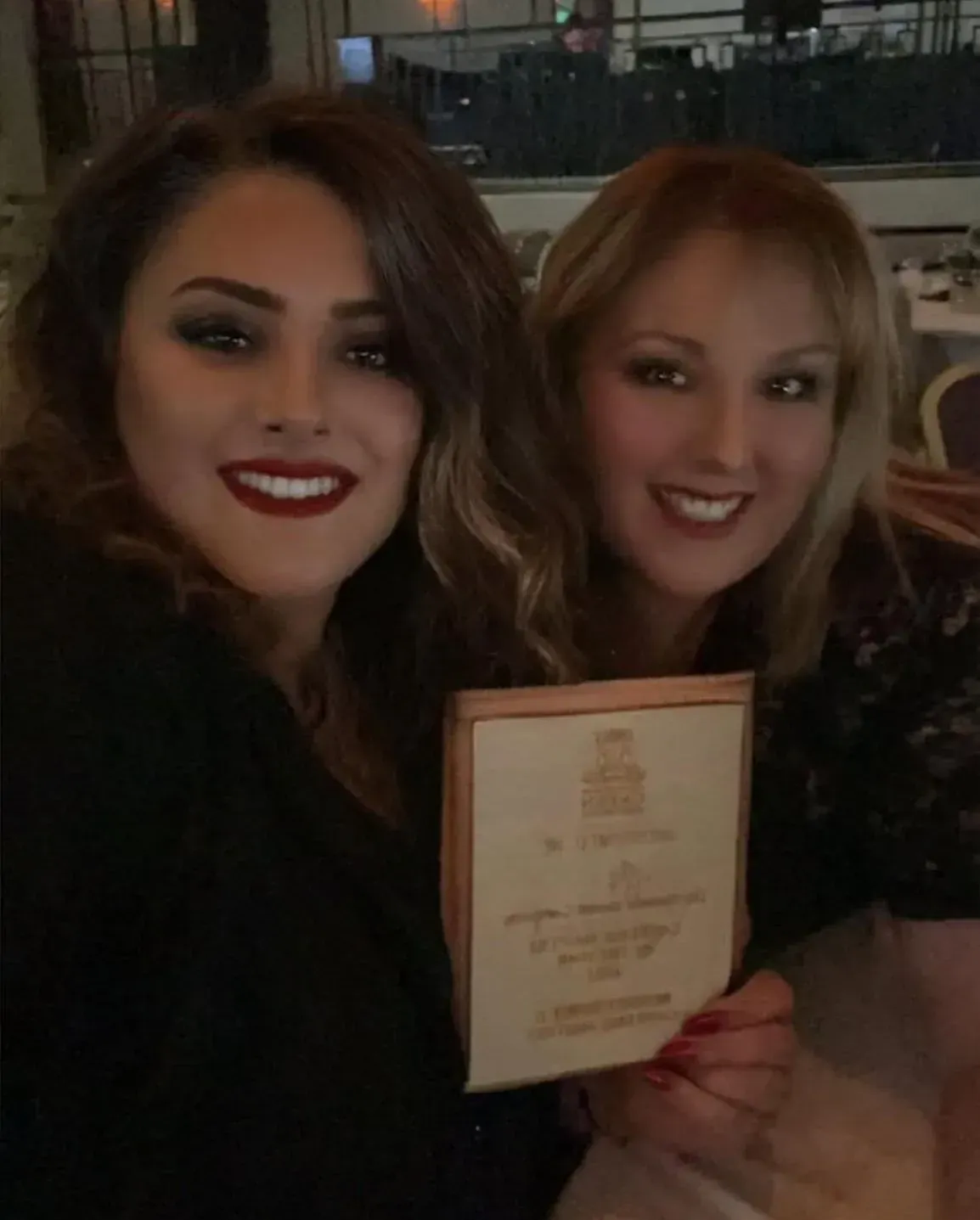 Two women are posing for a picture while holding a certificate.