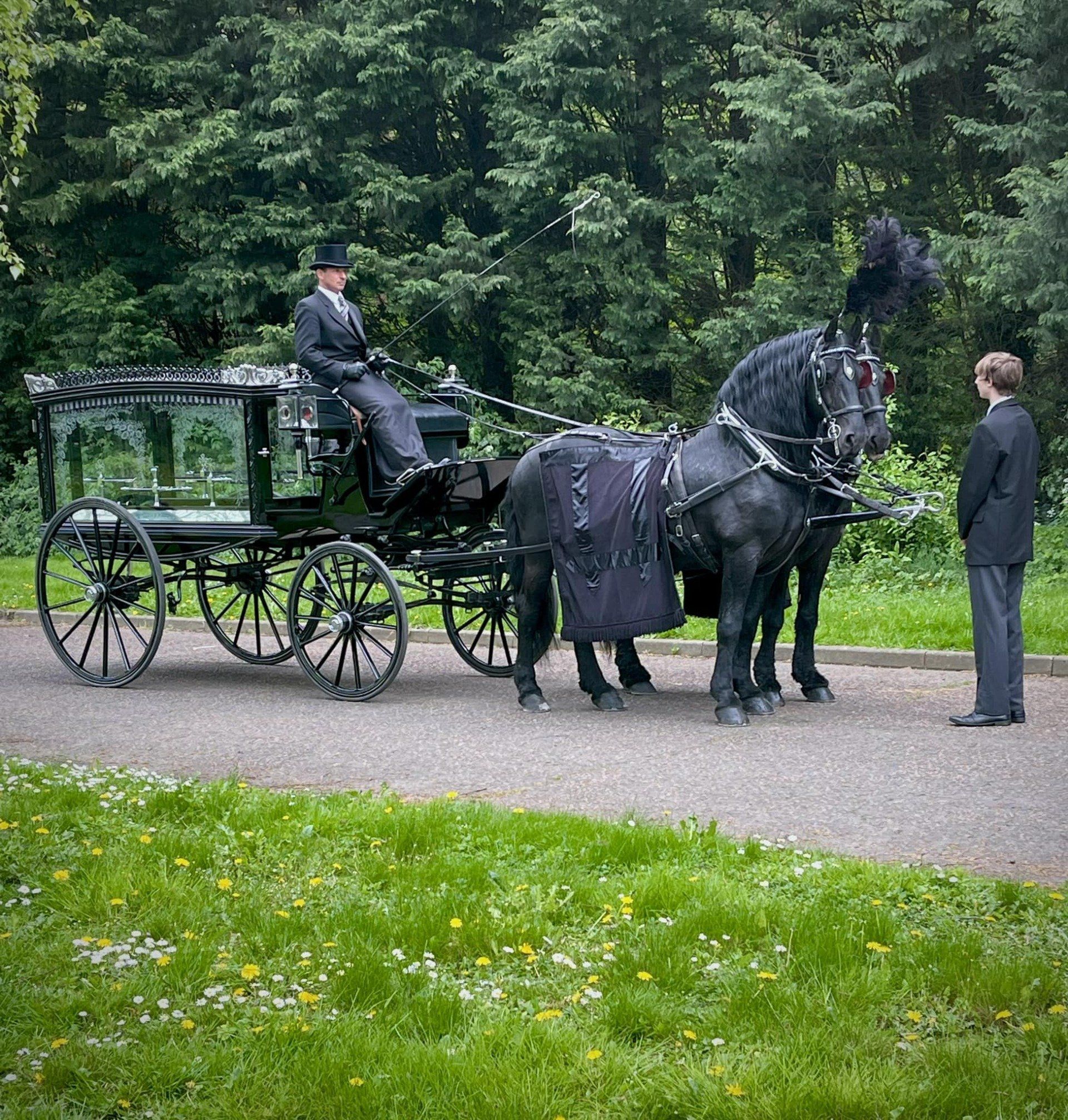 A horse drawn carriage with a man in the driver 's seat