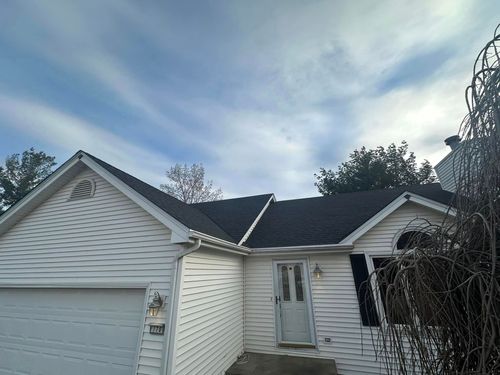 A white house with a black roof and a white garage door