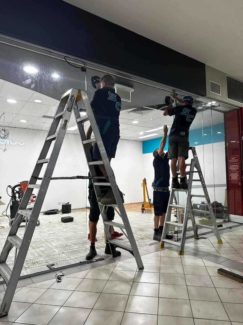 Four Men Installing A Glass Door In A Room — SC Glass & Aluminium in Yandina, QLD
