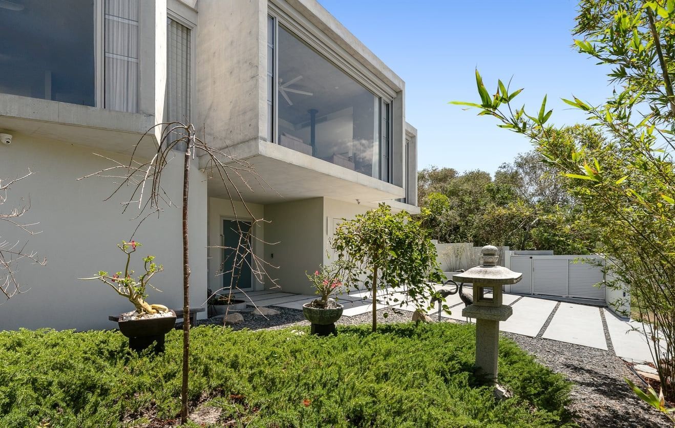 Modern multi-story home with a zen-inspired front garden, stone lantern, potted trees, and minimalist landscaping — SC Glass & Aluminium in Yandina, QLD