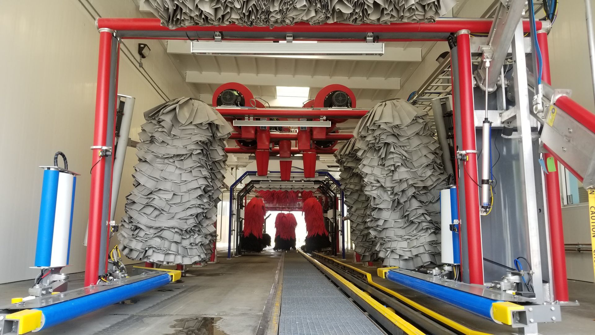 Inside of an automated car wash, red framework with brushes, blue/yellow rails.