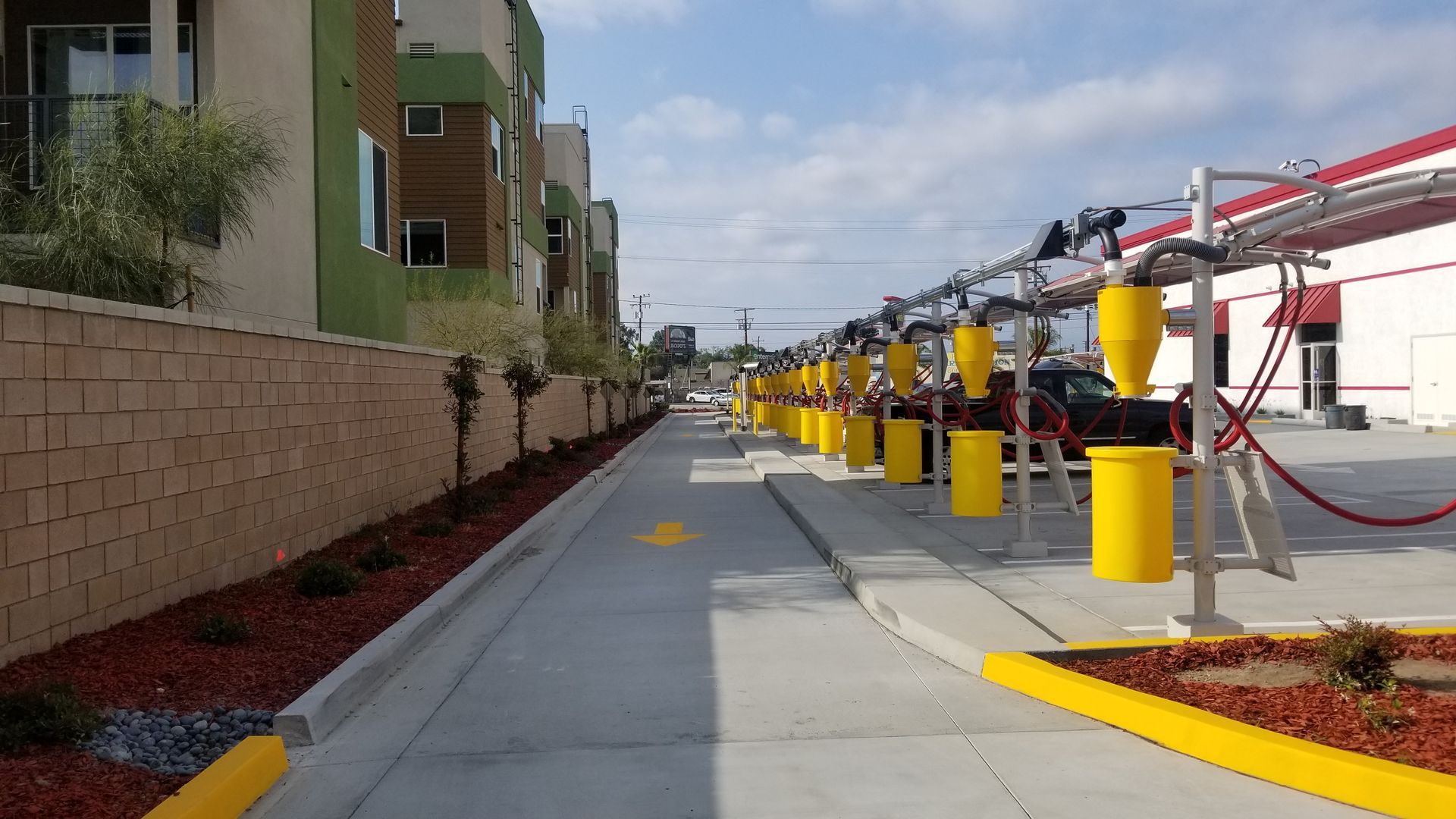 Car wash bays with yellow detailing next to a building with beige and green walls.