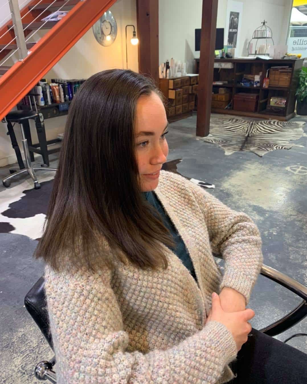 A Woman In A Sweater Is Sitting In A Chair In A Salon — Minnie & Lucille Hairdressing In Armidale, NSW