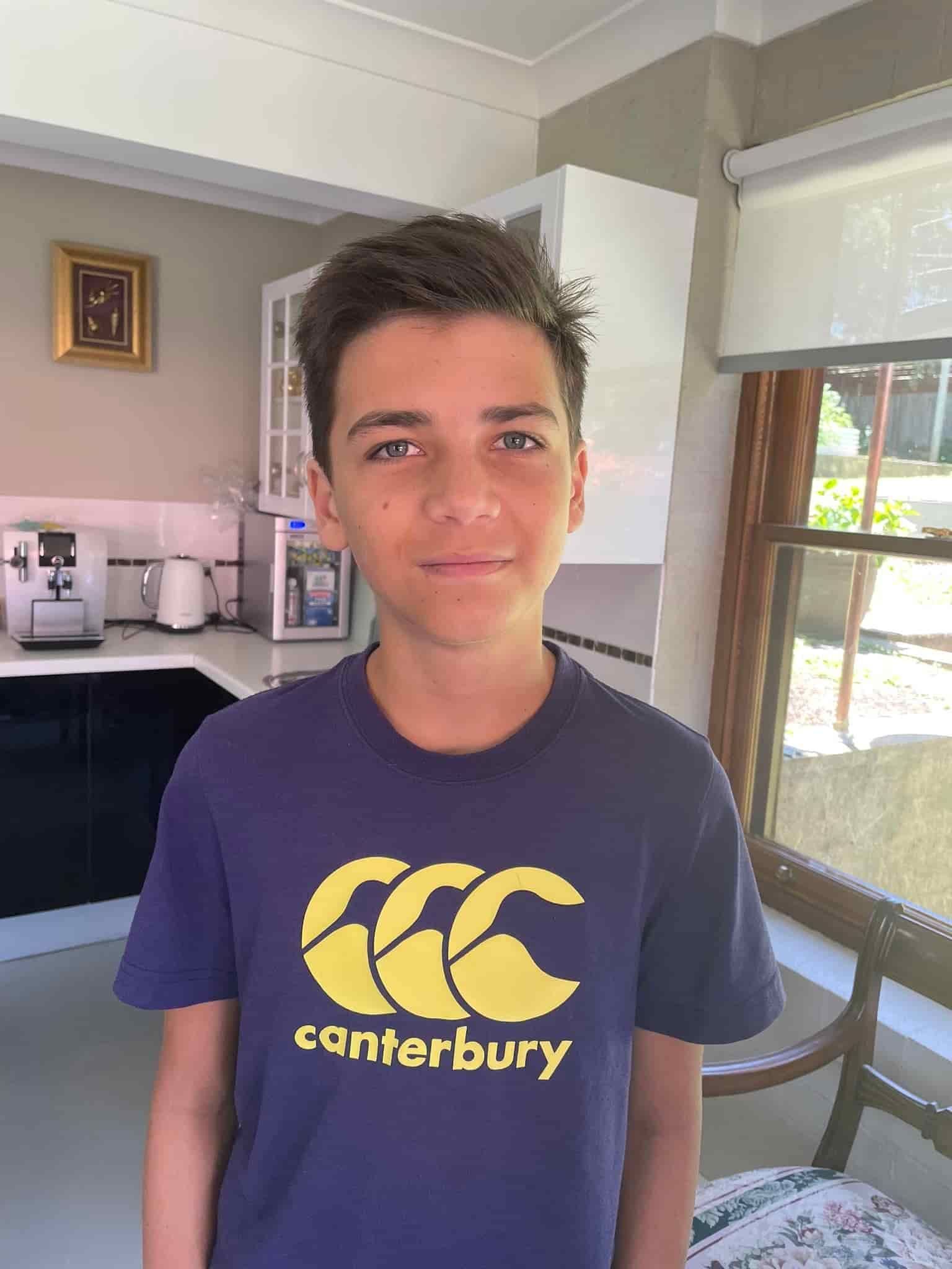 A Young Boy Wearing A Canterbury T-shirt Is Standing In A Kitchen — Minnie & Lucille Hairdressing In Armidale, NSW