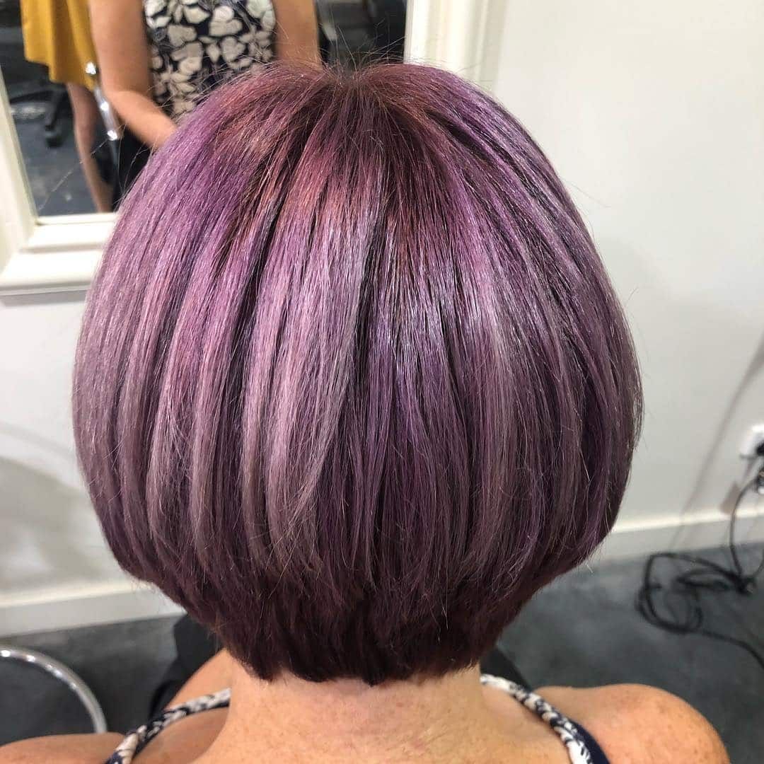 A Woman With Purple Hair Is Sitting In Front Of A Mirror — Minnie & Lucille Hairdressing In Armidale, NSW
