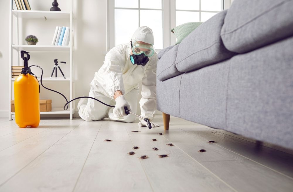 A man in a protective suit is cleaning a living room floor.