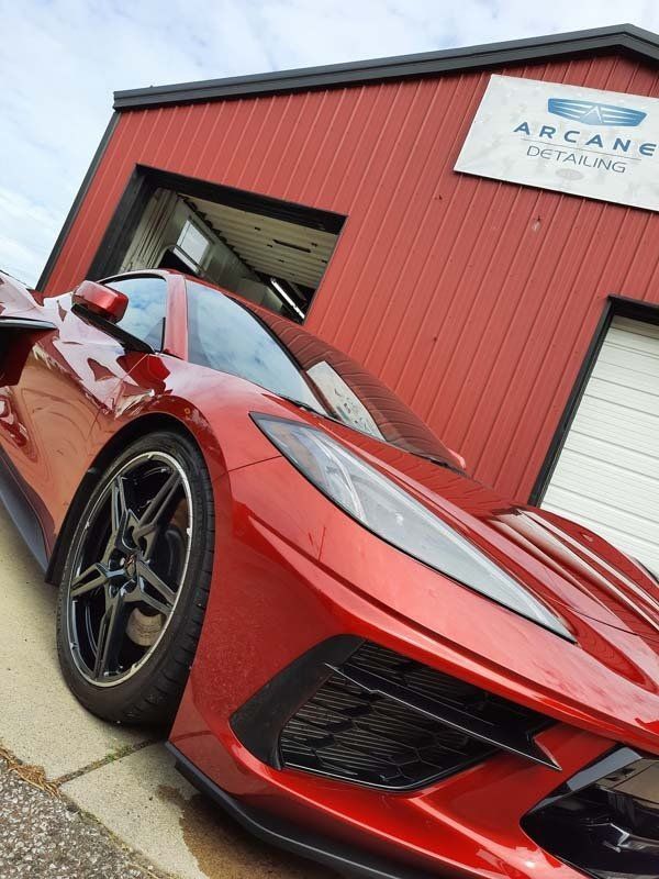 Red sports car parked in front of a red building, detailing shop sign above the door.