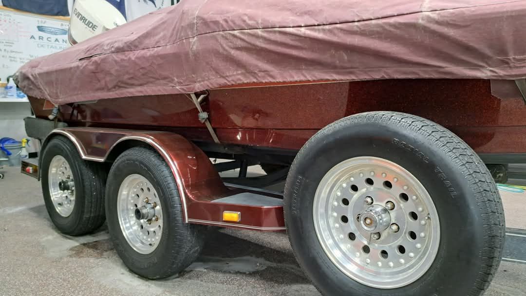 A boat is sitting on a trailer with a cover on it.