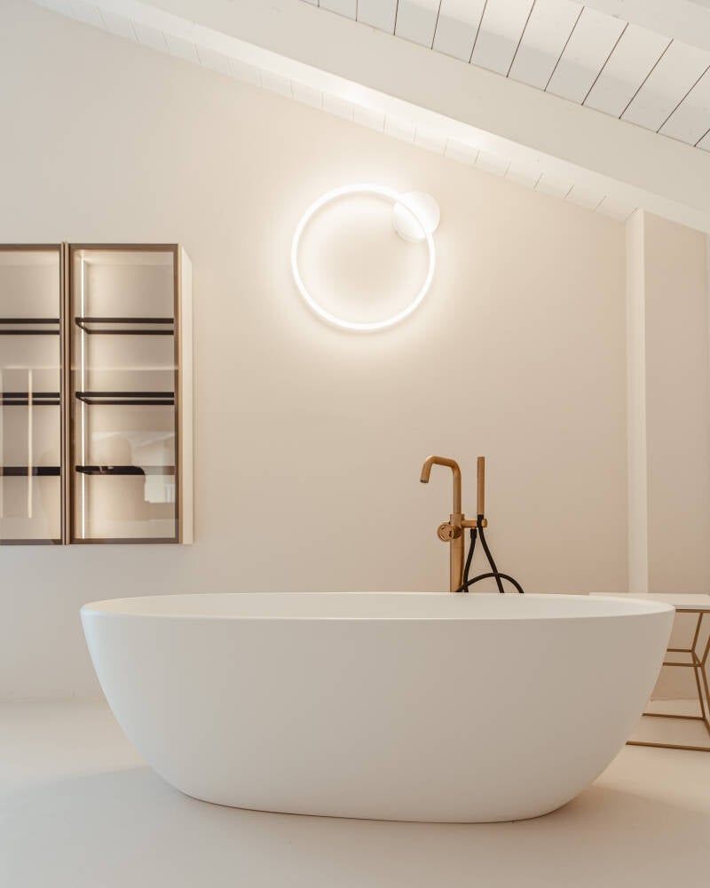 Moderno bagno bianco con lampada circolare sopra una vasca indipendente.