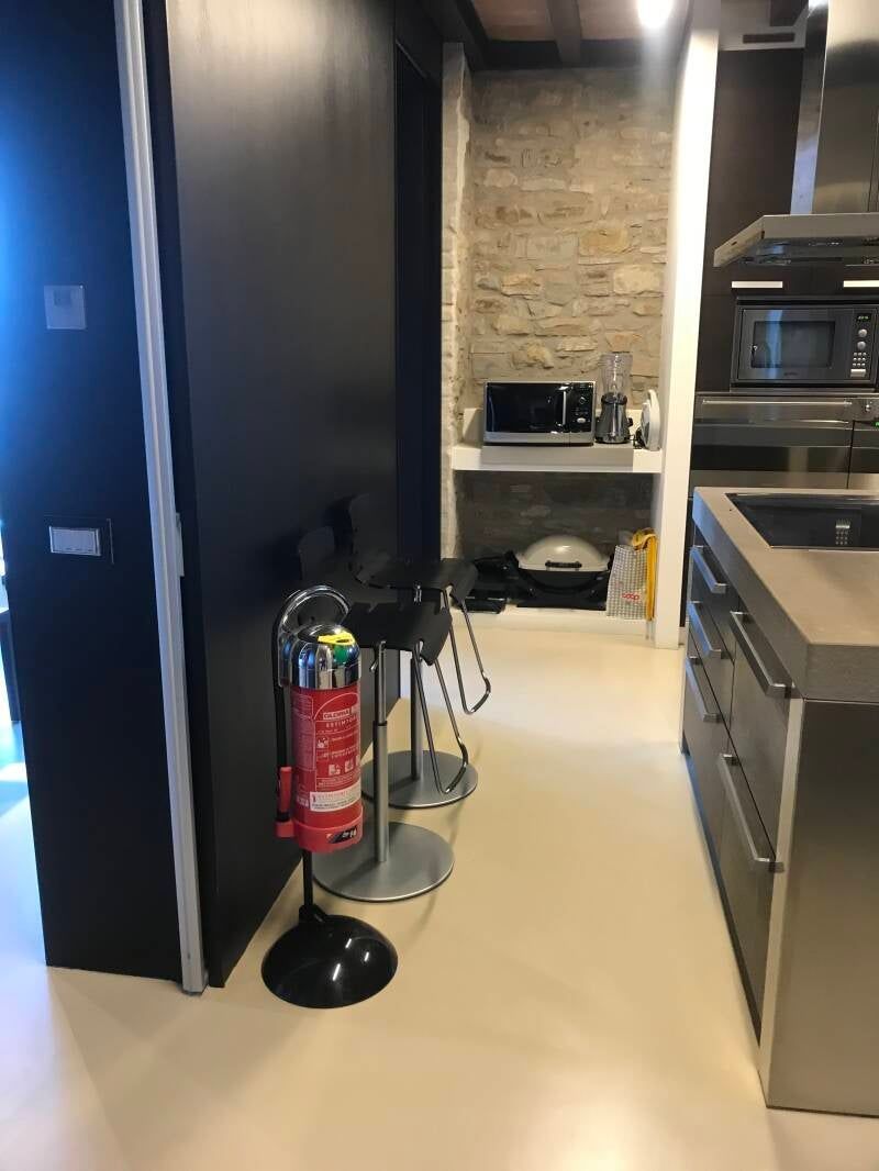 Un estintore sulla porta della cucina. Sono visibili sgabelli da bar e un forno a microonde.