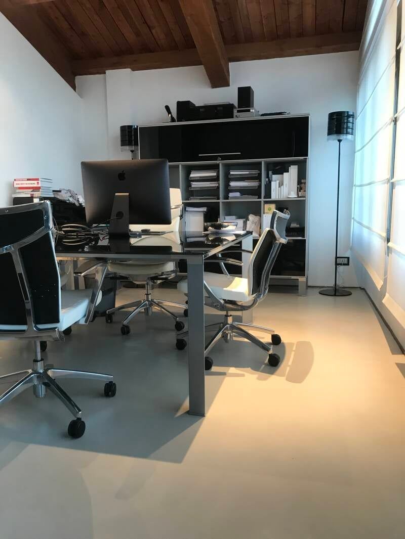 Ufficio moderno con scrivania, computer, sedie, scaffali e lampada da terra, con soffitto con travi in ​​legno.