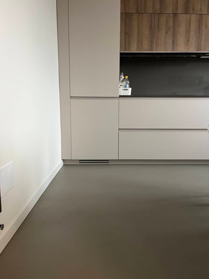 Cucina moderna con mobili grigio chiaro e pensili in legno, pavimento grigio.