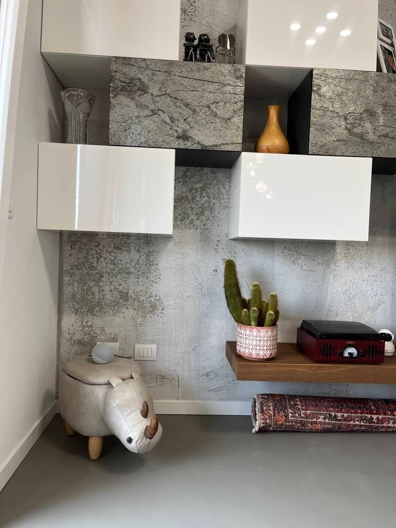 Soggiorno moderno con mensole a parete, mobili bianchi e un design decorativo in blocchi di cemento.