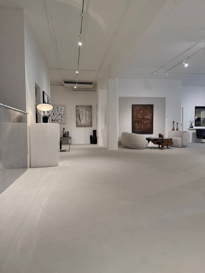 Vista interna di una galleria d'arte moderna con pareti bianche e arredi minimalisti. Le opere d'arte sono esposte alle pareti.