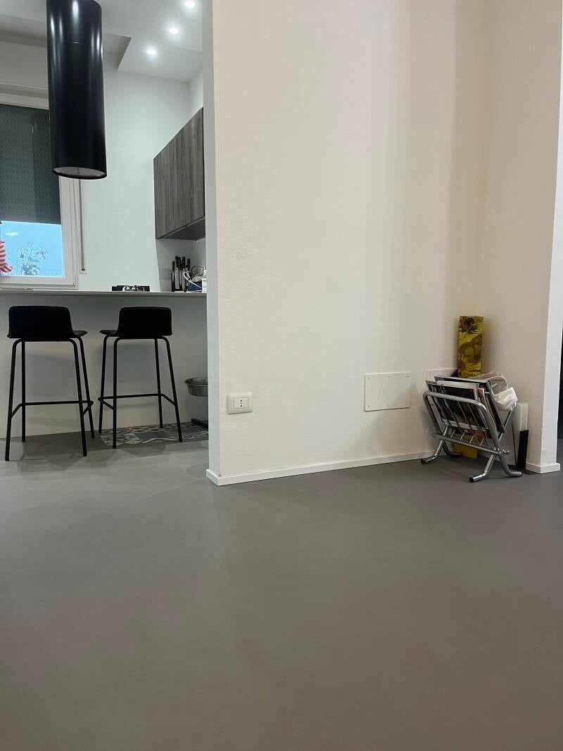 Vista interna: cucina con sgabelli da bar, portabottiglie e colori neutri.