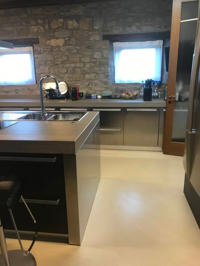 Cucina moderna con parete in pietra, isola con lavello ed elettrodomestici in acciaio inossidabile.