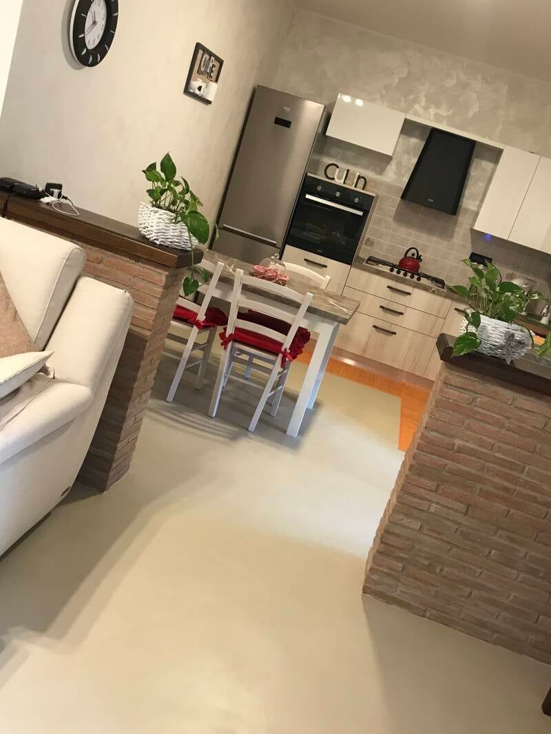 Cucina moderna con mobili bianchi, elettrodomestici in acciaio inossidabile e tavolo da pranzo.