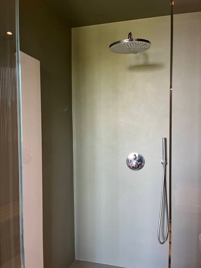 Cabina doccia moderna con soffione a pioggia, accessori cromati e pareti in vetro satinato.