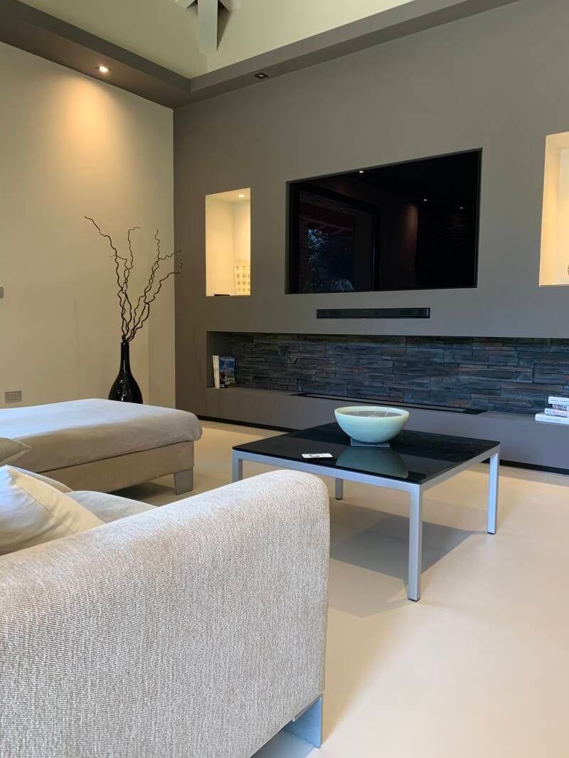 Soggiorno moderno con grande TV, toni neutri e arredamento minimalista.