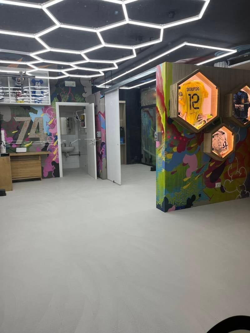 Interni moderni con luci esagonali sul soffitto, pareti con graffiti colorati e pavimento bianco.