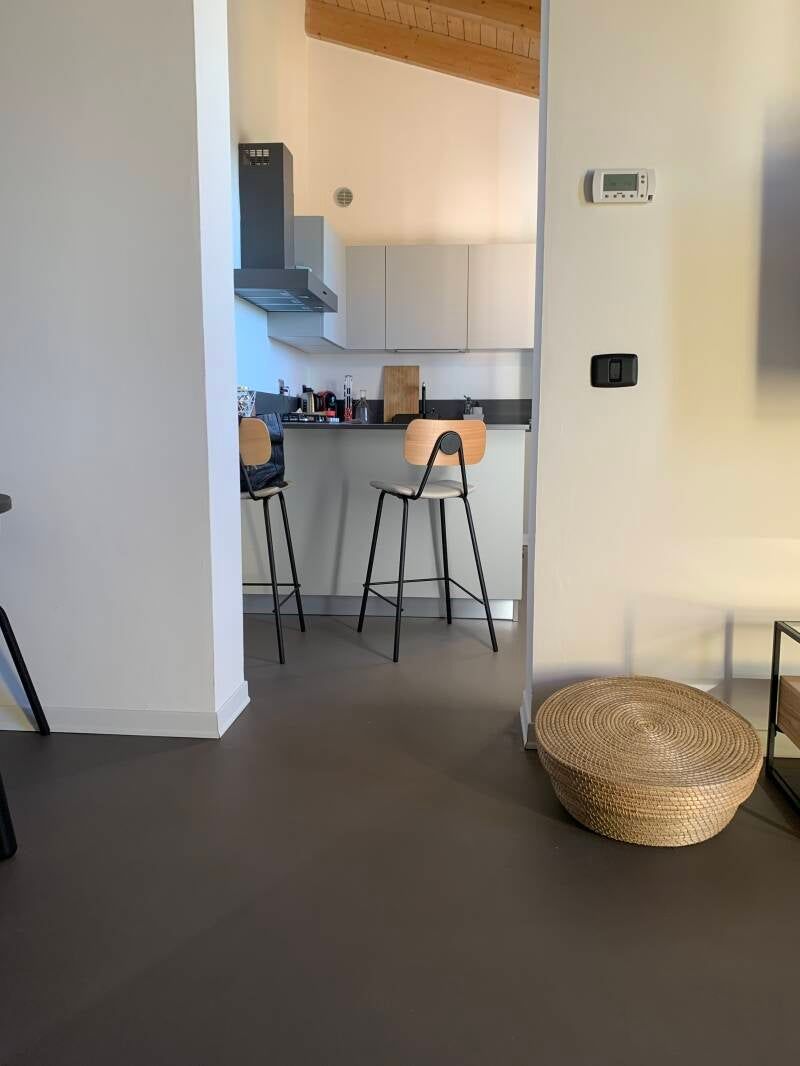 Vista della cucina con due sgabelli da bar e mobili grigi. Un cesto intrecciato è appoggiato sulla destra.