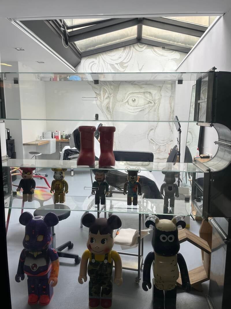 Vetrina in vetro con varie statuette da collezione e stivali rossi, in un interno luminoso e moderno.