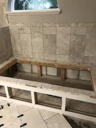 Bathtub niche under construction, wood frame, tile surround, and a window.