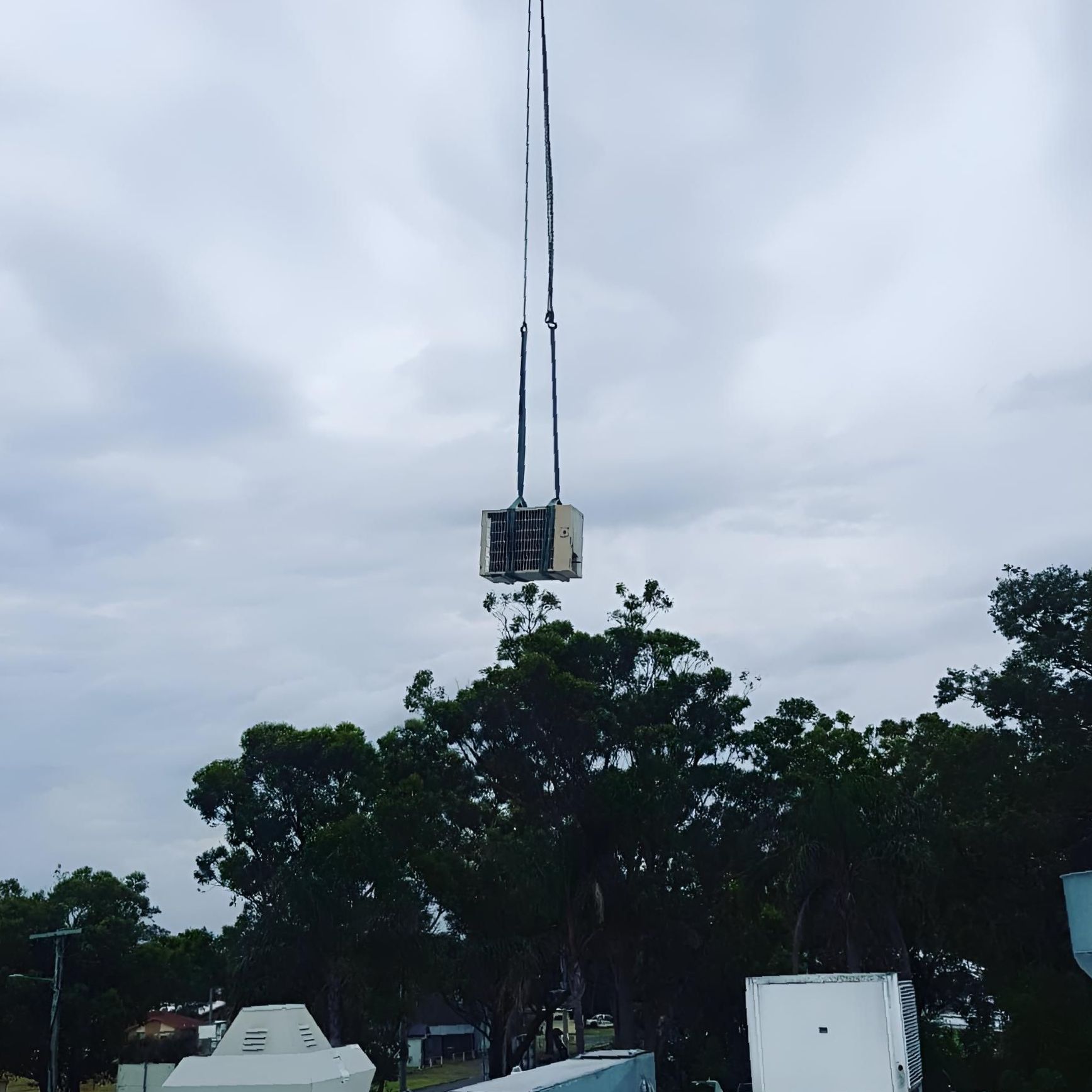 A Crane is Lifting an Air Conditioner Into the Air — Atmosphere Air Conditioning & Refrigeration In Medowie, NSW
