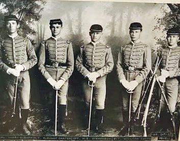 A group of men in military uniforms are standing next to each other holding swords.