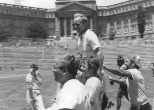 A man is carrying a woman on his shoulders in a black and white photo.