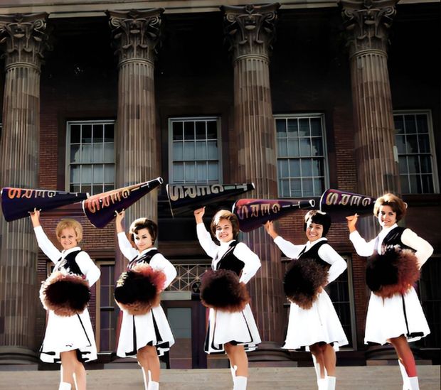 A group of cheerleaders holding pom poms with the letter e on their shirts