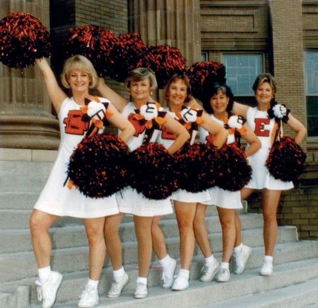 A group of cheerleaders holding pom poms with the letter e on their shirts