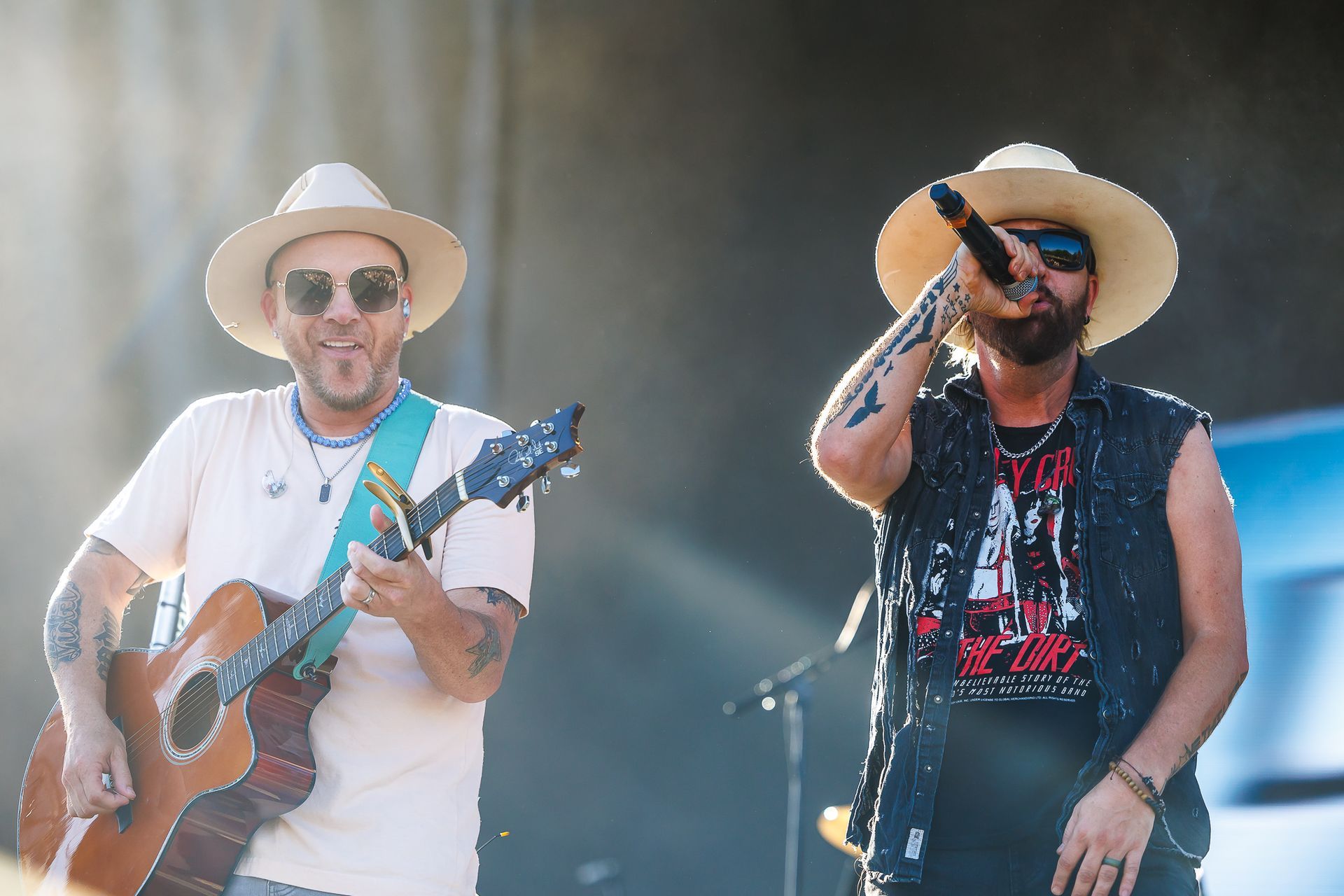 Two men are playing guitars and singing into microphones on a stage.