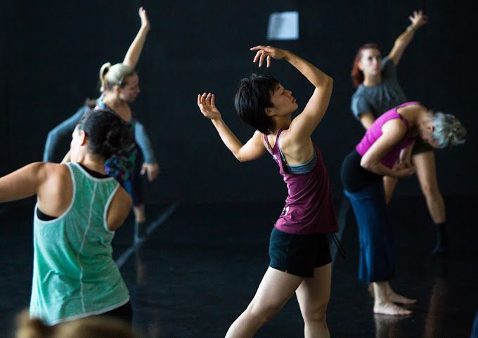 A group of women are dancing in a dark room.