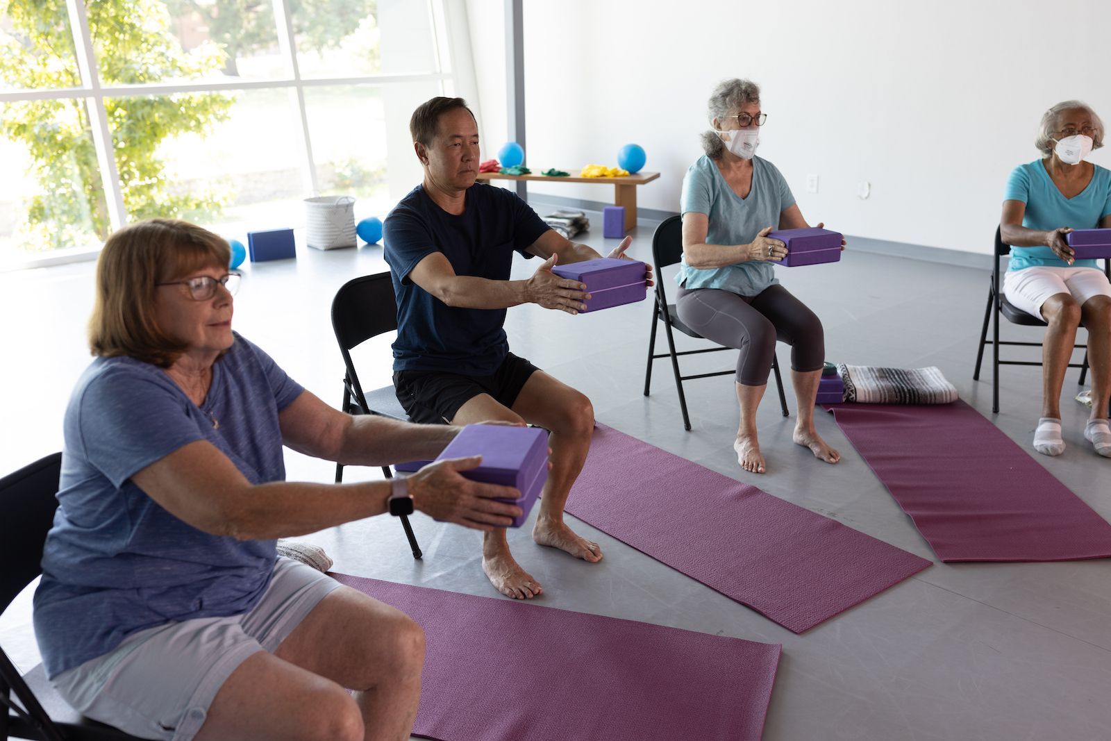 A group of people are sitting on yoga mats in a room.