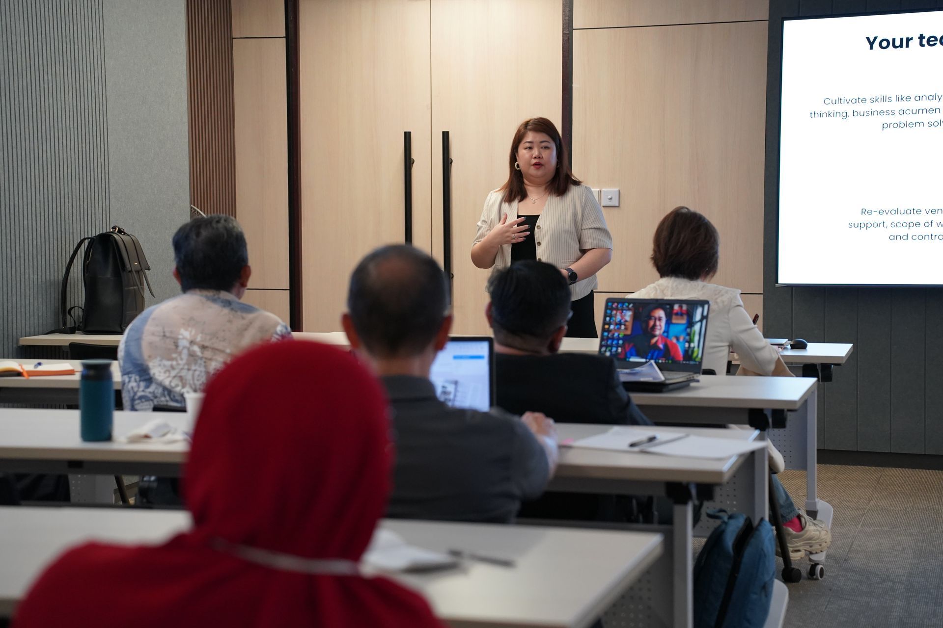 A woman giving a presentation to a group of people in a classroom.