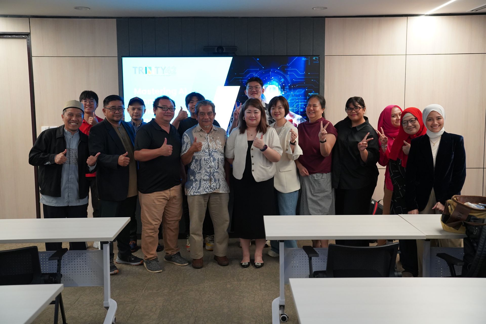 Group of people in a conference room giving thumbs up in front of a screen.