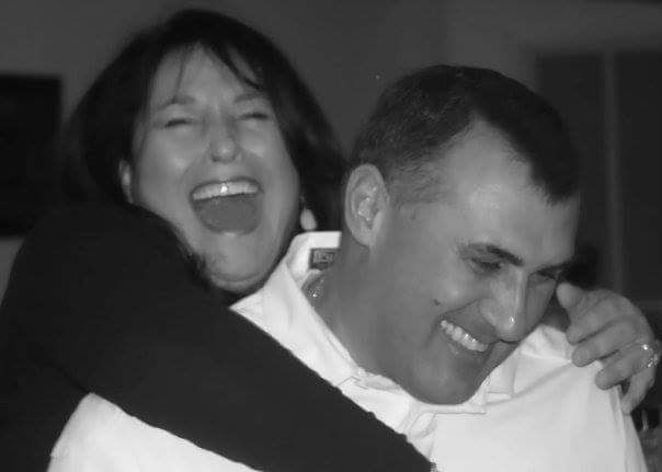 A black and white photo of a woman hugging a man